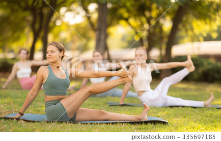 Various yoga poses performed by slender girls in the fresh air in summer garden Various yoga poses performed by slender girls in the fresh air in summer garden 135697185