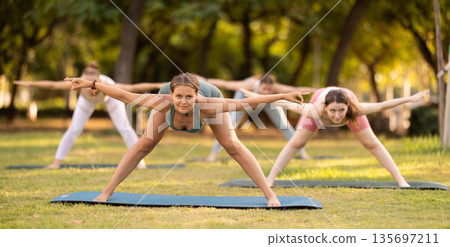 Yoga lesson visitors girls perform Himavanasana in park Yoga lesson visitors girls perform Himavanasana in park 135697211
