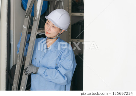 Female worker carrying a stepladder Female worker carrying a stepladder 135697234