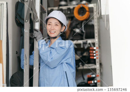Female worker carrying a stepladder Female worker carrying a stepladder 135697246