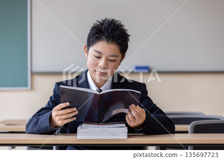 A student opening a reference book A student opening a reference book 135697723