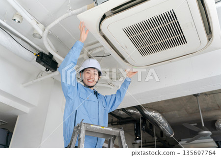 A female worker inspecting an air conditioner 135697764