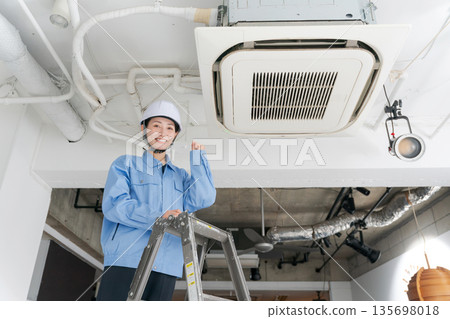 A female worker inspecting an air conditioner A female worker inspecting an air conditioner 135698018