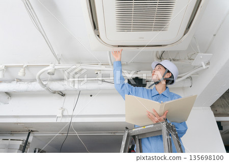 一名女工正在檢查空調 一名女工正在檢查空調 135698100