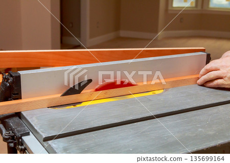 Worker is cutting wooden plank on table saw in attention to detail is clear as saw blade moves through wood DIY Worker is cutting wooden plank on table saw in attention to detail is clear as saw blade moves through wood DIY 135699164