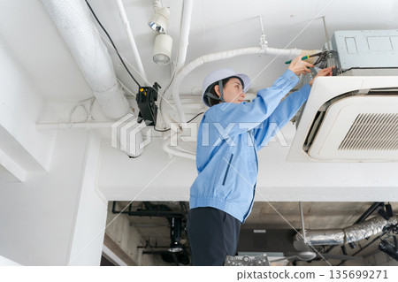 一名女工正在檢查空調 一名女工正在檢查空調 135699271