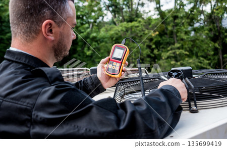 Technician use hand-held anemometer measuring air flowing measurement Technician use hand-held anemometer measuring air flowing measurement 135699419