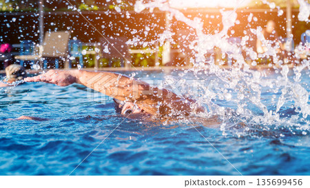 Young athletic man swimming in the swimming pool 135699456