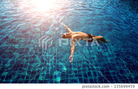 Young athletic man swimming in the swimming pool 135699459