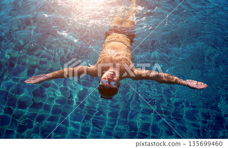 Young athletic man swimming in the swimming pool 135699460