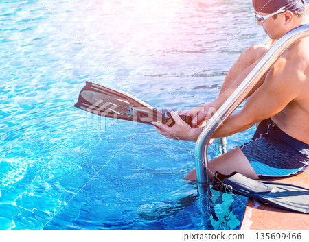 Young athletic man wearing flippers by the pool Young athletic man wearing flippers by the pool 135699466