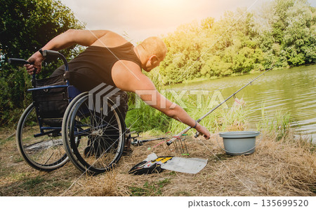 Handicapped man fishing at a lake. Wheelchair camping. 135699520