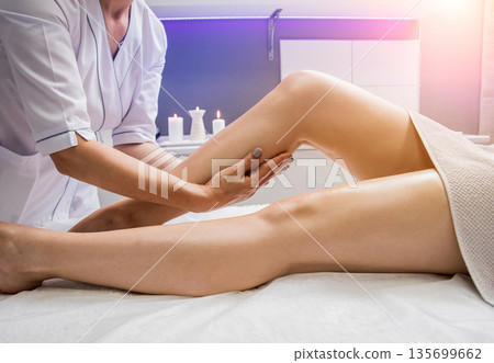 Beautiful young woman enjoying legs massage with oil in spa salon. Cosmetology 135699662