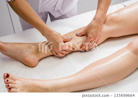 Beautiful young woman enjoying legs massage with oil in spa salon. Cosmetology 135699664
