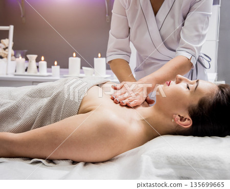 Beautiful young woman enjoying massage in spa salon. Cosmetology 135699665