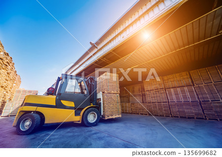 Forklift loader load lumber into a dry kiln. Wood drying in containers. Forklift loader load lumber into a dry kiln. Wood drying in containers. 135699682