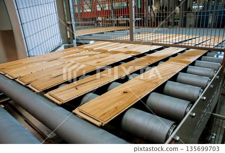 Production line of the wooden floor factory. CNC automatic woodworking machine. Production line of the wooden floor factory. CNC automatic woodworking machine. 135699703