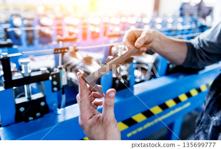 Male hands hold vernier caliper and measure steel collar. 135699777