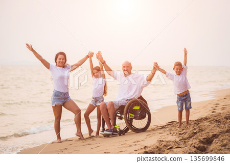 Disabled man in a wheelchair with his family on the beach. 135699846