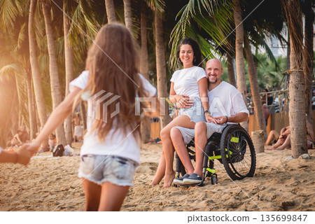 Disabled man in a wheelchair with his family on the beach. 135699847