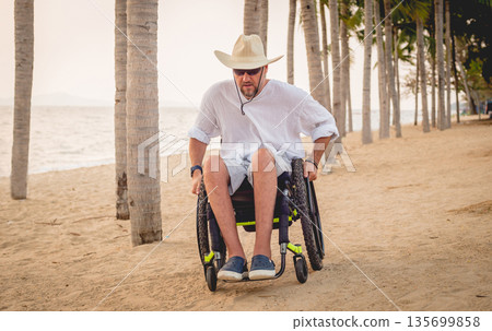 Disabled man in a wheelchair on the beach. Disabled man in a wheelchair on the beach. 135699858