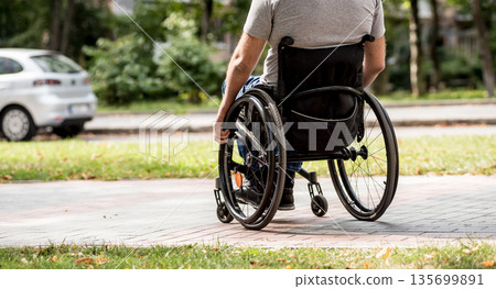 Handicapped man in wheelchair walk at the park alley 135699891