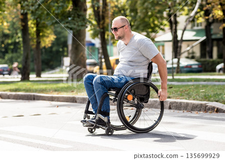 Handicapped man in wheelchair crossing street road Handicapped man in wheelchair crossing street road 135699929
