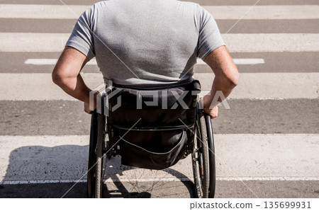 Handicapped man in wheelchair crossing street road Handicapped man in wheelchair crossing street road 135699931