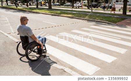 Handicapped man in wheelchair preparing to cross the road on pedestrian crossing 135699932
