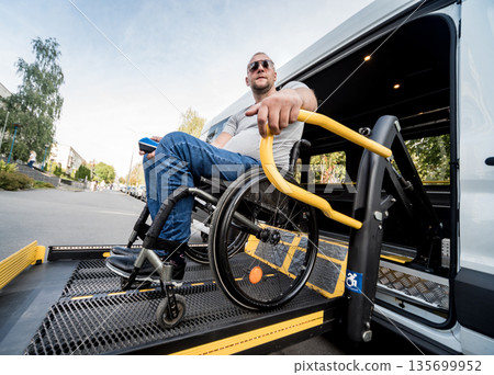 A man in a wheelchair on a lift of a vehicle for people with disabilities 135699952