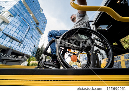 A man in a wheelchair on a lift of a vehicle for people with disabilities 135699961