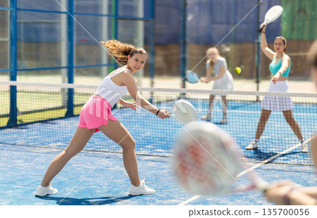 Woman playing with other paddle tennis players Woman playing with other paddle tennis players 135700056