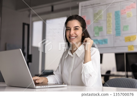Portrait of smiling attractive Latina female manager working using laptop Portrait of smiling attractive Latina female manager working using laptop 135700076