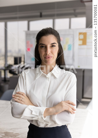 Professional businesswoman standing confidently in modern office 135700081