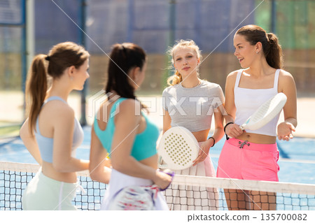 Female padel tennis players chatting on tennis court 135700082