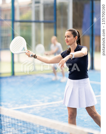 Adult woman playing doubles padel tennis 135700160