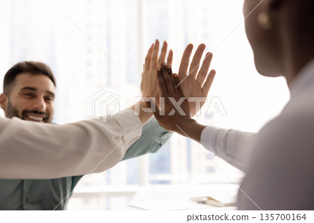 Multiracial teammates celebrate success, stacking their palms together Multiracial teammates celebrate success, stacking their palms together 135700164