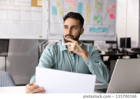 Man analyzing data and summarizing information with pensive expression 135700166