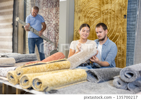 Couple man and woman choosing carpet in store Couple man and woman choosing carpet in store 135700217