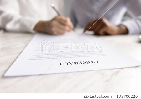 Female places signature on contract paper, close up 135700220