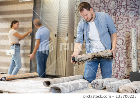 Young man choosing carpet in building store Young man choosing carpet in building store 135700223