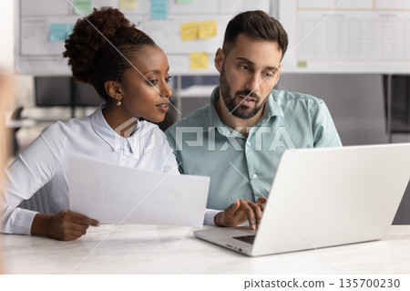 Colleagues cross-checking agreement details with information on laptop 135700230