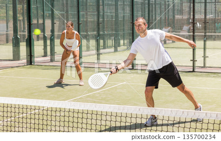 Sports woman and man playing padel on tennis court Sports woman and man playing padel on tennis court 135700234
