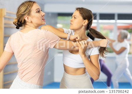 Two young women training self-defense techniques Two young women training self-defense techniques 135700242