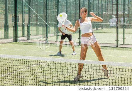 Young woman and man playing doubles padel 135700254