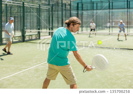 Adult men playing padel against two men Adult men playing padel against two men 135700258