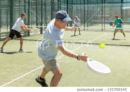 Adult and young men playing padel against two men Adult and young men playing padel against two men 135700345
