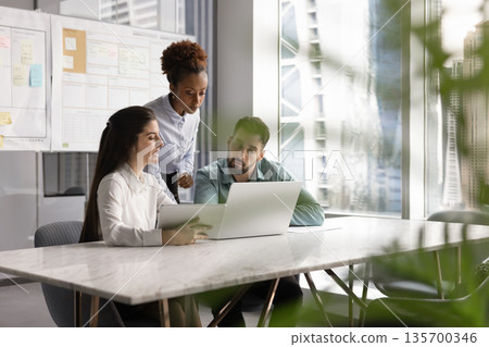 Colleagues take part in briefing using laptop and digital tablet 135700346