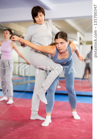 Self-defense training - women practice doing painful holds 135700347