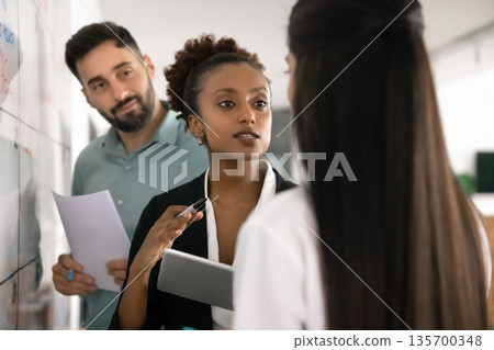 African woman engaging in strategic planning session with teammates 135700348